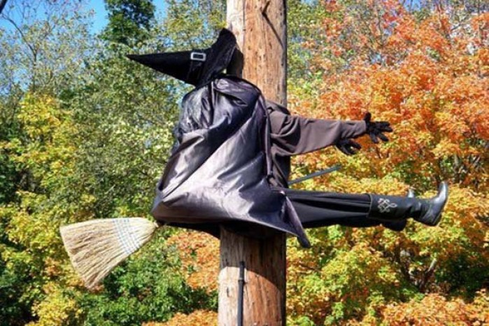 bruxa voando com sua vassoura e trombando num poste