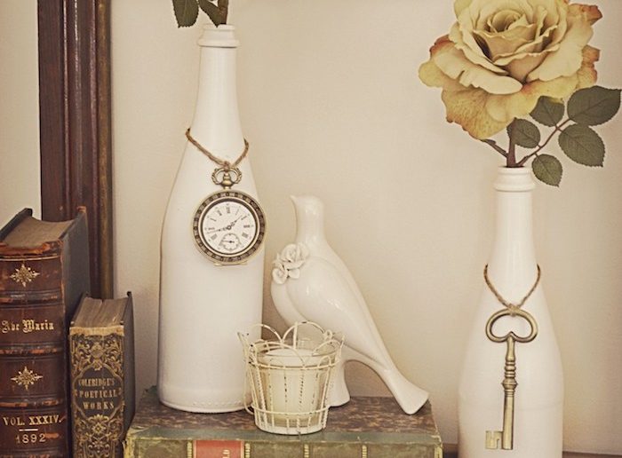 garrafas pintadas de branco sendo suporte de decoração