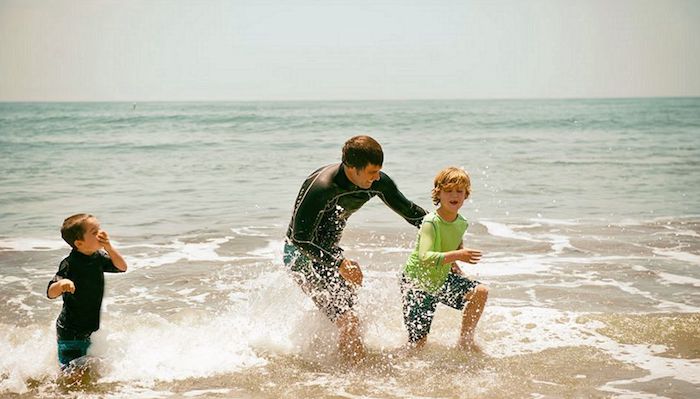 Como limpar a roupa de banho e os equipamentos para esportes aquáticos pai e filhos brincando na orla do mar